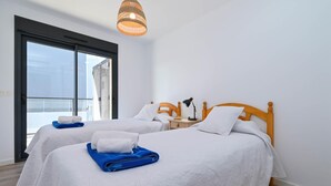 A hotel room with two beds, a large window, and a hanging light fixture.