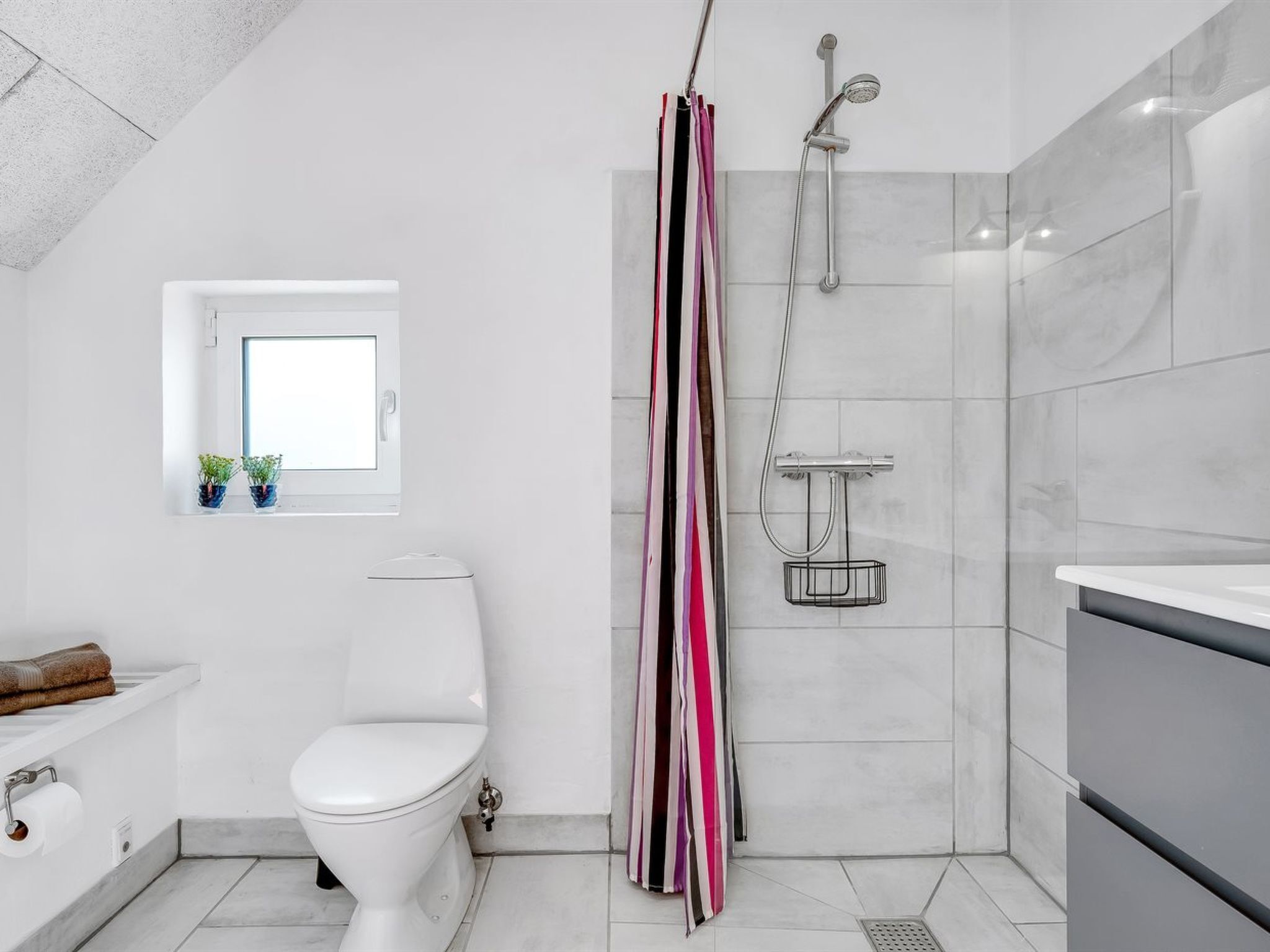 Une salle de bain moderne équipée de toilettes, d’une douche et d’un lavabo.
