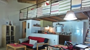 A cozy living area with a wooden sofa, a small table, and a kitchen in the background. - 2 Annexed Apartments -private Place to Swim-large Terrace- Unlimited View (Platanias)