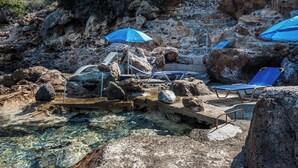 A rocky pool area with clear water, blue umbrellas, and lounge chairs. - 2 Annexed Apartments -private Place to Swim-large Terrace- Unlimited View (Platanias)
