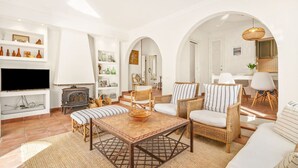 Una sala de estar con televisión, muebles de mimbre y una chimenea.