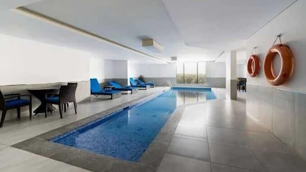 A modern indoor swimming pool with blue water, surrounded by lounge chairs and a sunbed. - Karim Hotel Al Olya (Al Khobar)