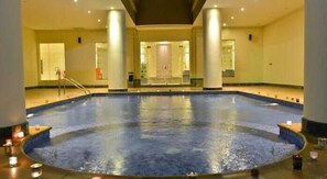 A large indoor swimming pool with a central staircase, surrounded by pillars and candles. - Karim Hotel Al Olya (Al Khobar)