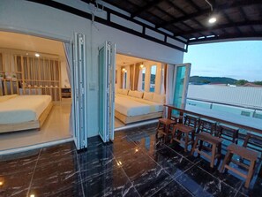 Una habitación de hotel moderna con una cama grande, un balcón con muebles de madera y vistas al paisaje.