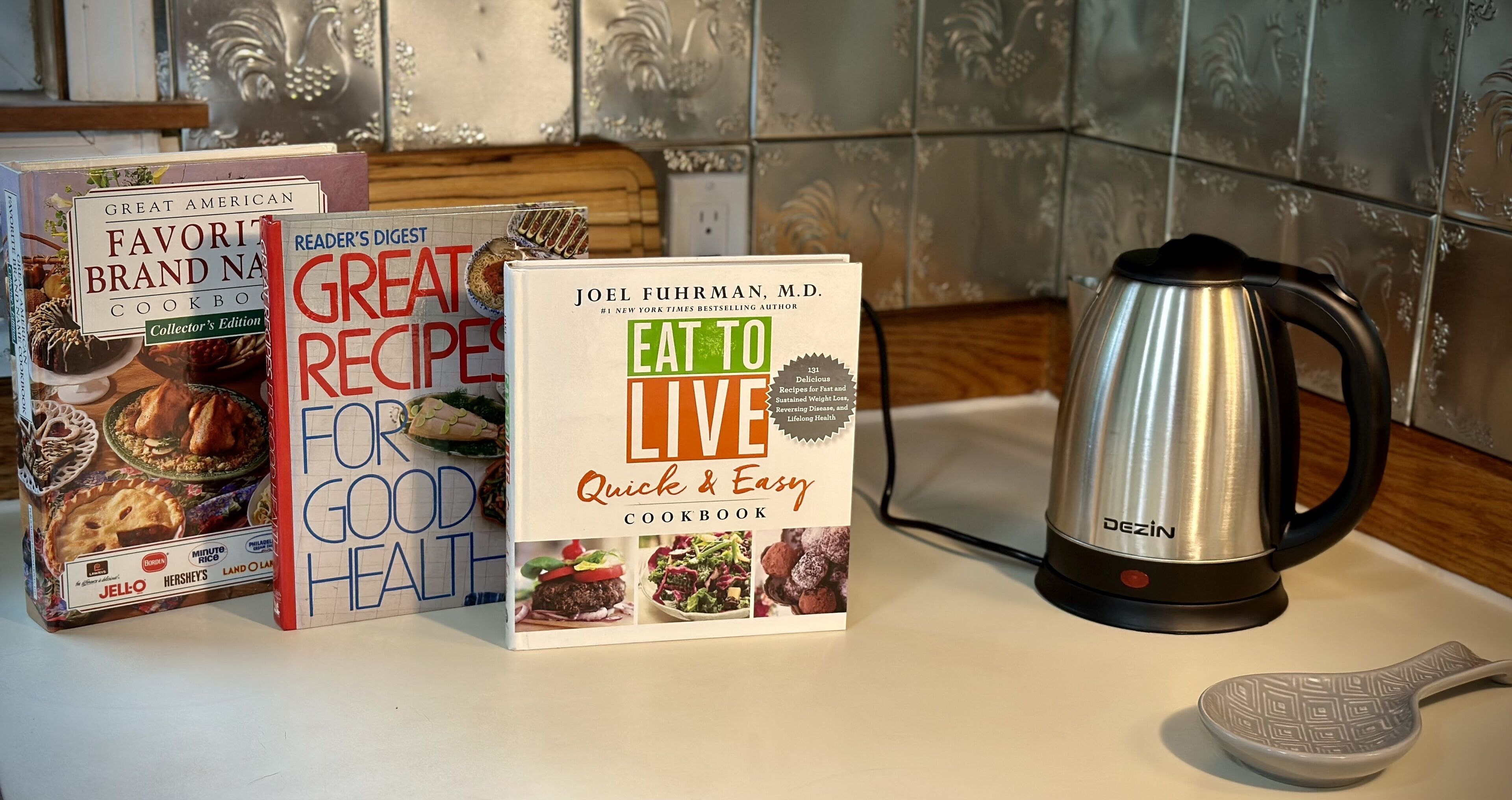 Eine Küchenarbeitsplatte mit einer Kaffeemaschine, einem Kochbuch mit dem Titel „EAT TO LIVE Quick & Easy“ sowie zwei weiteren Kochbüchern.