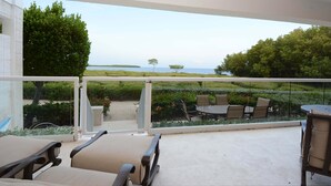 Un balcon aménagé avec du mobilier d’extérieur, une vue sur la mer et une végétation bien entretenue.
