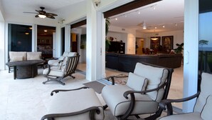 Un grand salon comprenant un canapé, des fauteuils, une table basse et un téléviseur.