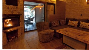 A cozy room with a stone fireplace, a sofa, and a wooden coffee table. - Kulübem Etkinlik ve Konaklama (Ankara)