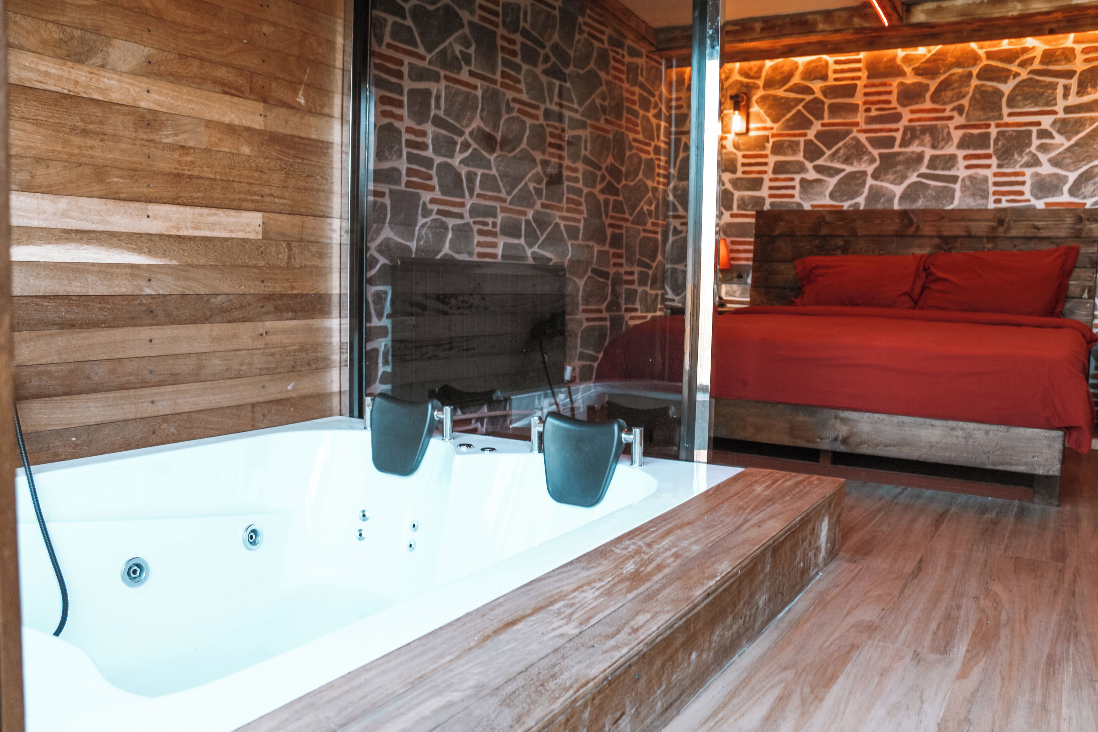 A modern bathroom with a stone wall, wooden paneling, and a large bathtub.