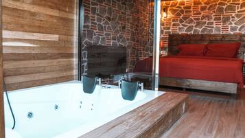 A modern bathroom with a stone wall, wooden paneling, and a large bathtub.