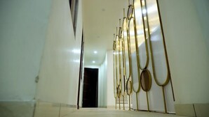 A hallway with a reflective floor and a series of golden, oval-shaped wall decorations. - Hotel Lyf Suites - bahadurgarh (Bahadurgarh)