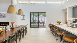 Una cocina moderna con una isla grande, taburetes de bar y un comedor con sillas y una mesa.