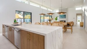 Eine moderne Küche mit einer großen Kochinsel, Holzschränken und einem Essbereich mit Tisch und Stühlen.