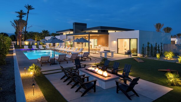 A modern outdoor pool area with lounge chairs, a fire pit, and a dining area.