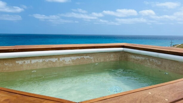 Ein freier Blick auf ein Schwimmbad mit Holzterrasse und Meerblick.