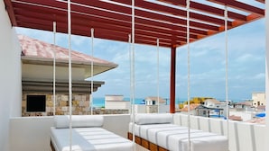 Ein Balkon mit zwei Hängematten, einer Steinmauer und Blick aufs Meer.