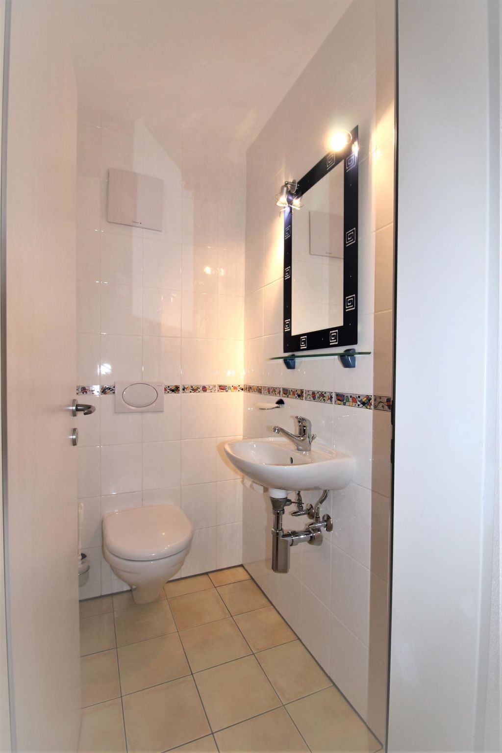 Ein kleines, sauberes Badezimmer mit Toilette, Waschbecken und Spiegel.