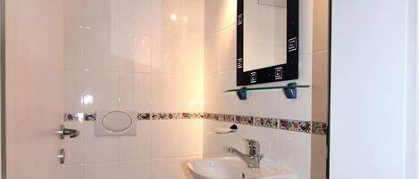 Ein kleines, sauberes Badezimmer mit Toilette, Waschbecken und Spiegel.