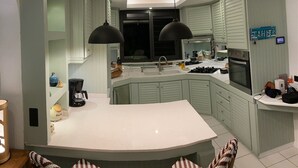 Une cuisine moderne dotée d’un îlot central, de luminaires suspendus et offrant une vue sur l’extérieur.