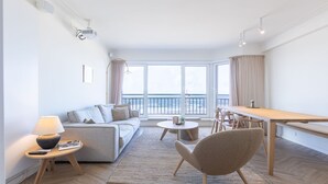 Un saló modern amb un sofà, una taula de centre i una zona de menjador amb taula i cadires.