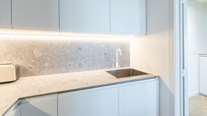 Una cuina moderna amb taulell de granat, un rentaplatets d'acer inoxidable i armaris blancs.