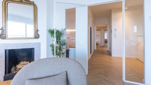 Un saló modern amb una llar de foc, un mirall gran i un passadís que condueix a una altra habitació.
