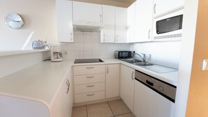 A compact kitchen with white cabinets, a microwave, a toaster, and a sink.