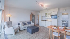 En moderne stue med sofa, skammel og spisebord til fire personer.