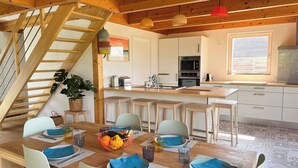 A modern kitchen with white cabinets, a central island, and a built-in oven.
