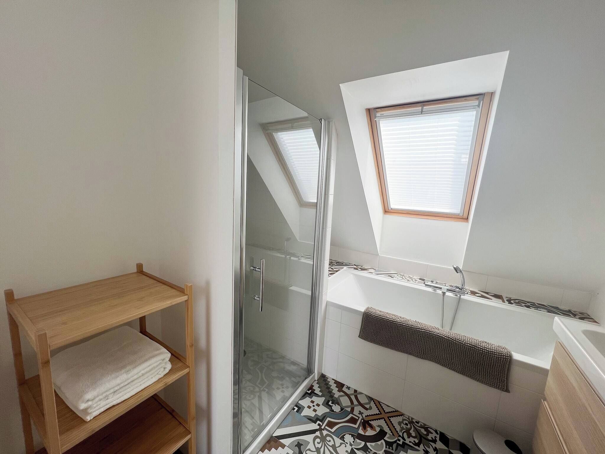 A small, modern bathroom with a shower, a built-in sink, and a window.