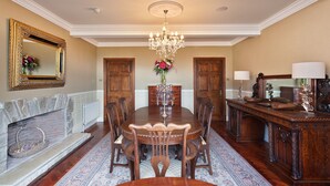 Un comedor formal con una gran mesa de madera, sillas, un candelabro y una chimenea.