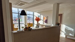 Un comptoir d’accueil avec une lampe, un vase de fleurs et des œuvres d’art encadrées accrochées au mur.