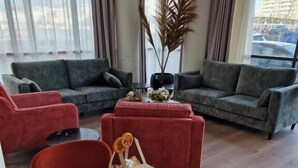 Un salon moderne avec des canapés gris, une table basse en bois et un fauteuil rouge.