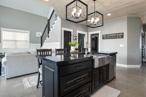A modern kitchen with a black island, stainless steel appliances, and a staircase leading to another level.