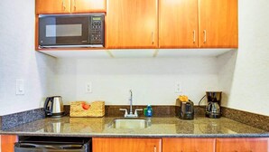 A kitchen with wooden cabinets, a microwave, a sink, and a dishwasher. - Sunny Isles Bliss: Beachfront Retreat for 4 (Sunny Isles Beach)