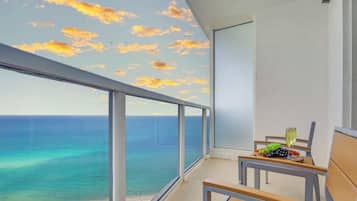 Un balcon avec vue sur l’océan et un ciel au coucher du soleil.