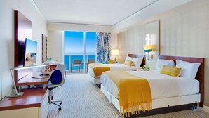 A hotel room with a bed, a desk, a chair, a television, and a view of the ocean. - Sunny Isles Bliss: Beachfront Retreat for 4 (Sunny Isles Beach)