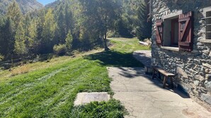 Edifici de pedra amb un camí de pedra que porta a una banca.