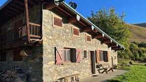 Un edifici de pedra amb balcons de fusta, una antena parabòlica i una banca a l'exterior.
