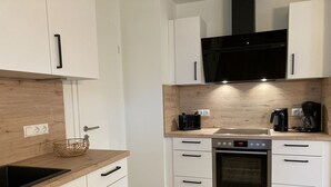 A modern kitchen with white cabinets, a wooden countertop, a built-in oven, and a black microwave. - Dahmer Dünen - Ostseezauber! (Dahme)