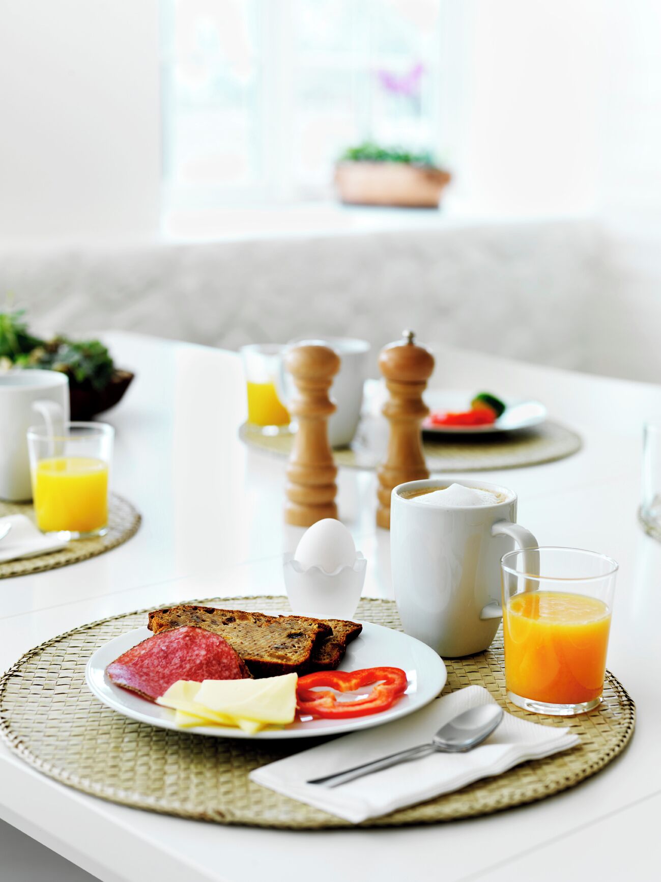 A breakfast setting with toast, eggs, tomatoes, and orange juice on a table.