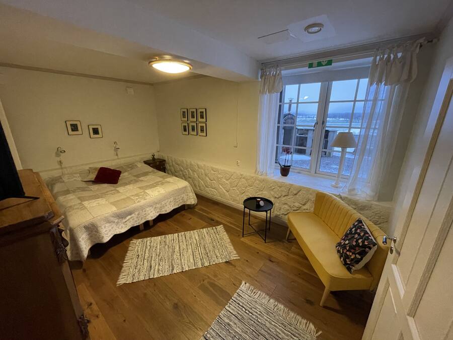 A bedroom with a bed, a sofa, a small table, and a window with a view.