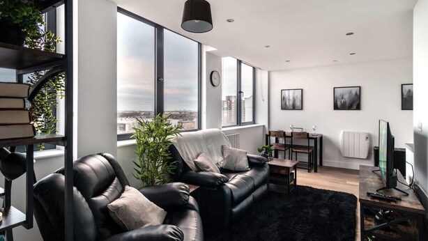 Una sala de estar moderna con sofá de cuero, una mesa de comedor y un ventanal con vista a la ciudad.