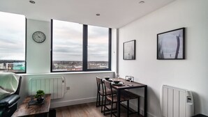 Una habitación moderna con una mesa de comedor, sillas, un reloj y un ventanal con vistas a la ciudad.