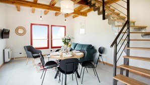 Un comedor con una mesa redonda, sillas y una escalera.