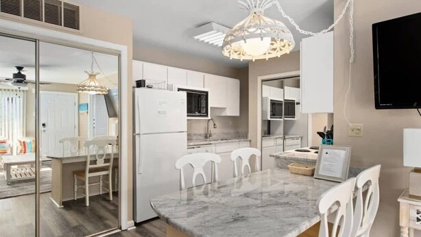 A modern kitchen with white cabinets, a marble countertop, and a pendant light. - Waterfront Ocean Villa! (Ocean City)