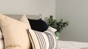 Ein Bett mit Kissen und einer Zimmerpflanze im Hintergrund.