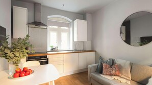 A modern kitchen with white cabinets, a stainless steel range hood, and a large window. - King Apartment · Courtyard Garden in Bath (Bath and North East Somerset)