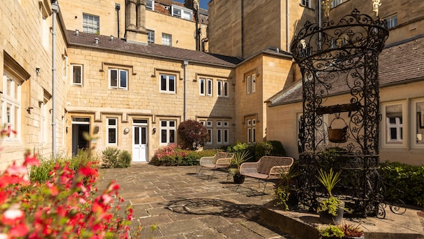 A courtyard with stone paving, a wrought iron gate, and a bench. - Cosy King Apartment · Central Bath (Bath and North East Somerset)