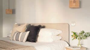 A neatly arranged bedroom with a bed, pillows, a bedside table with a book, and a vase with flowers. - Split-Level Deluxe Suite · Sleeps 4 in Bath (Bath and North East Somerset)
